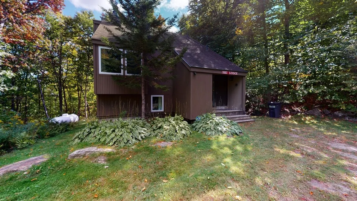 A wide exterior view of the lodge, front porch, and lush greenery, suggesting a relaxing yet adventurous atmosphere. The openness of the porch and the surrounding environment evoke a sense of retreat after a day outdoors.