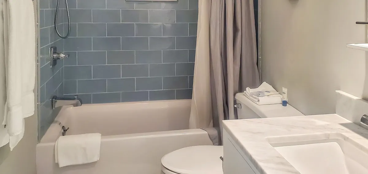 A soothing bathroom scene highlighted by a bathtub, sink, showerhead, and clean tiled surfaces. The mood is calm and tranquil, ideal for rejuvenating baths or showers after an outdoor adventure.