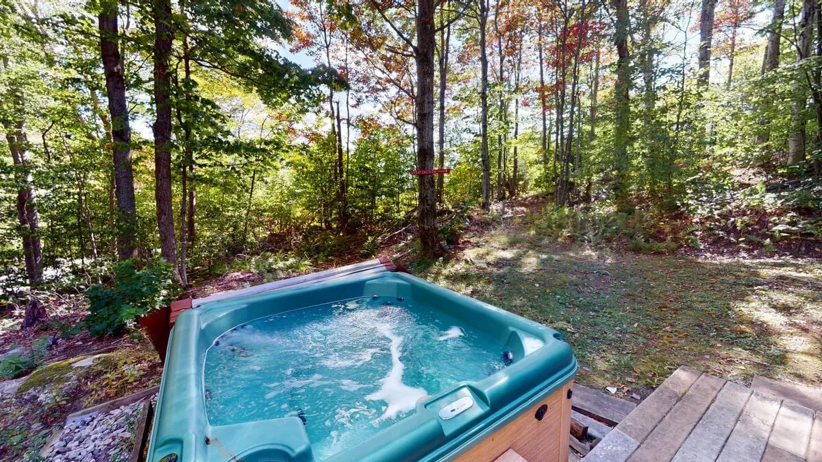 This image captures the outdoor hot tub set on a wooden deck, surrounded by lush trees. The bubbling water and tranquil forest backdrop evoke a sense of relaxation and privacy. The deck area invites guests to unwind, whether soaking in the tub or enjoying a morning coffee while immersed in nature.